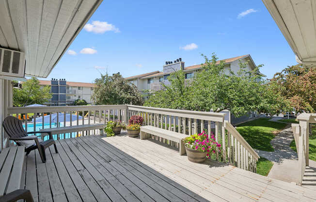 A wooden deck with a bench and a pool in the background.