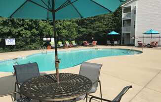 a swimming pool with a table and chairs under an umbrella