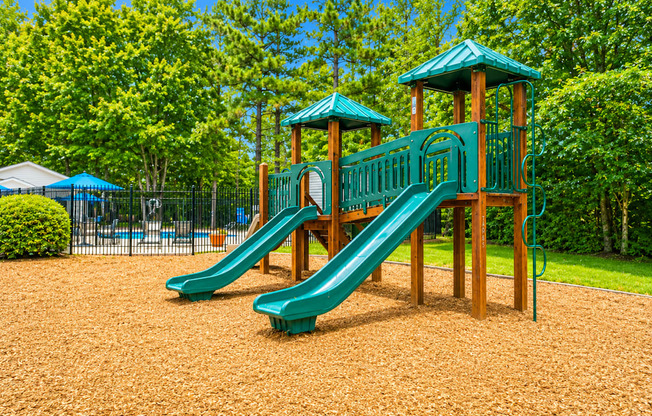 A playground with a green slide and wooden structure.