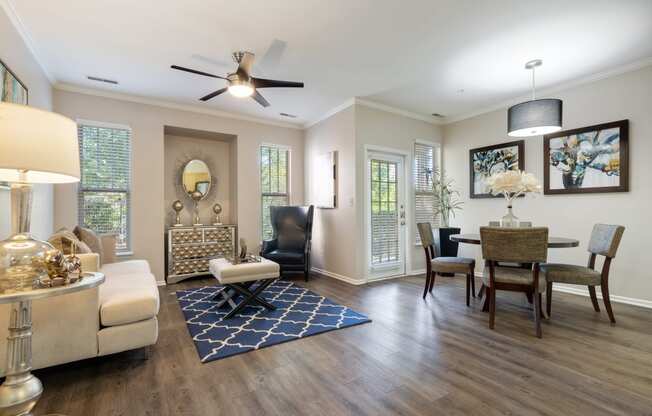 Pet-Friendly Apartments in Bolingbrook IL - The Meadows at River Run - Open, Spacious Living Area with Couch, Carpet, Ceiling Fan, Coffee table, Silver Decor, Lamps, Window, and Dining Table