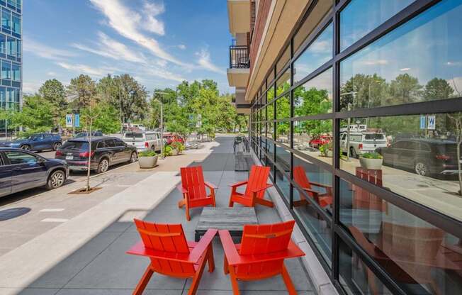 A glass building with red chairs and tables outside.