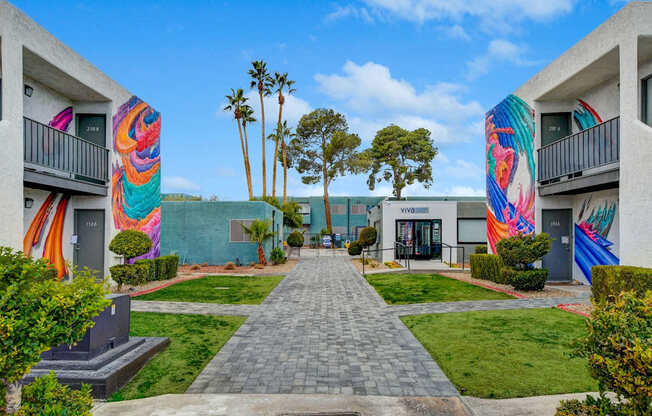 A walkway leads between two buildings with colorful murals on the walls.