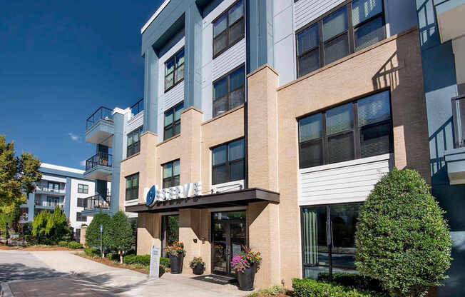 A modern building with a balcony and a small garden in front.