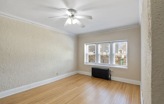 an empty living room with a ceiling fan and a window