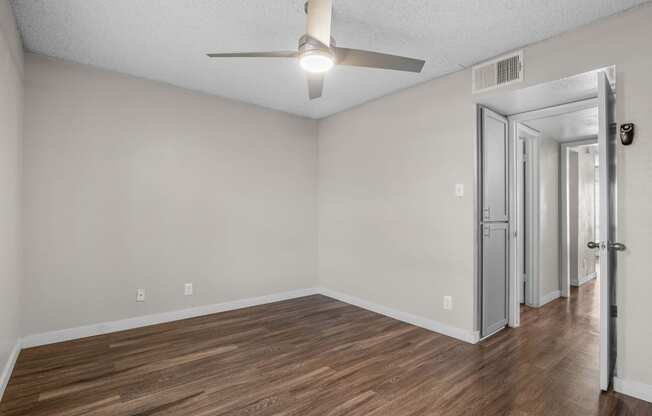 the spacious living room with white walls and a ceiling fan