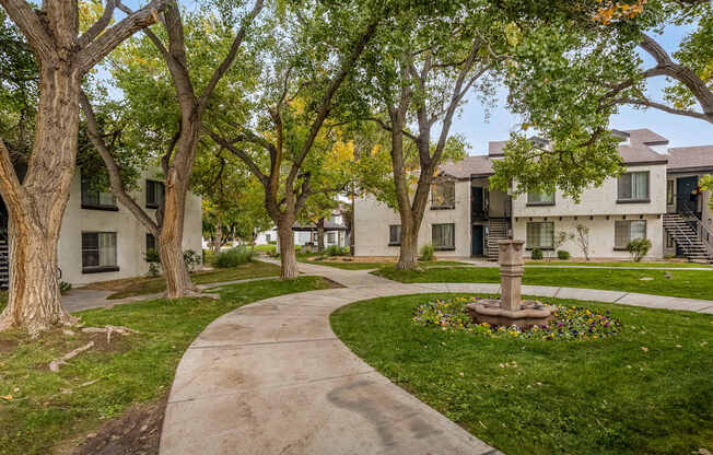 a sidewalk with trees and apartments in the background