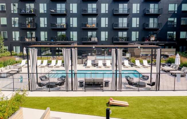 a pool with lounge chairs and grass in front of a building