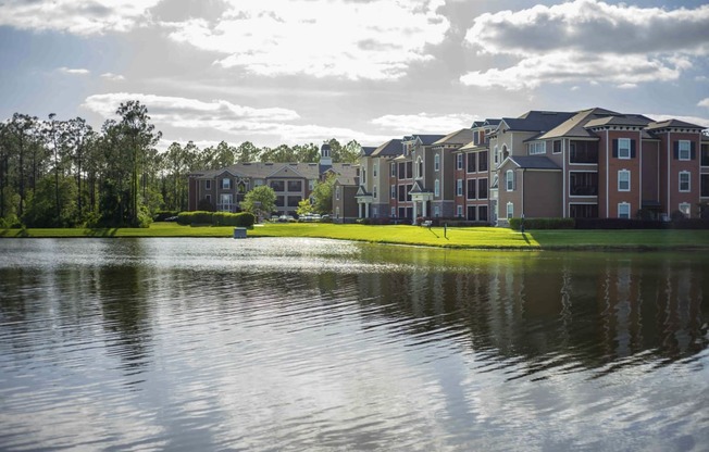 a row of houses on a field with a reflection of a city in the water