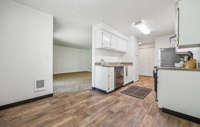 A kitchen with white cabinets and a wooden floor.