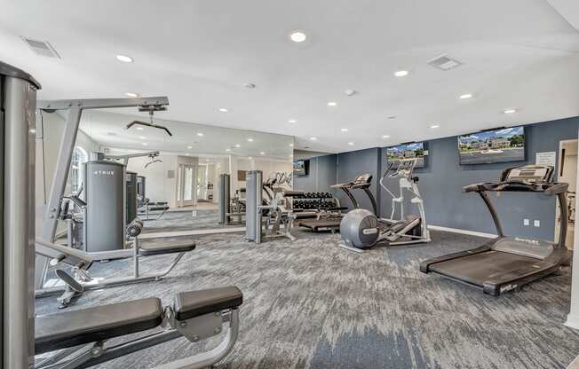 A spacious gym with a variety of equipment including treadmills, weight machines, and a rowing machine.