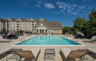 a swimming pool with chairs and a building in the background