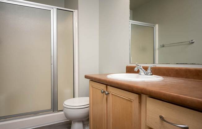 A bathroom with a toilet, sink, and mirror.