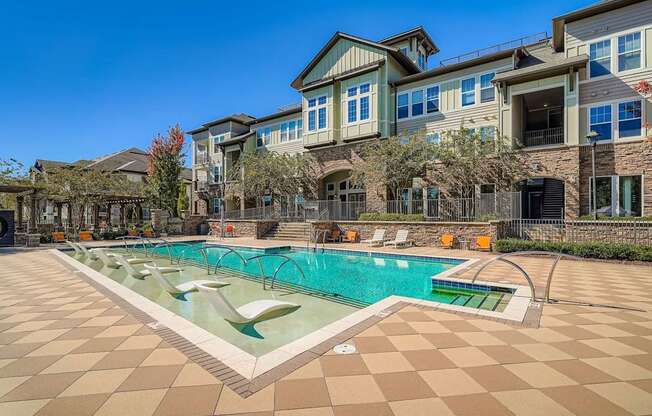 A large swimming pool in front of a building with a tiled floor.