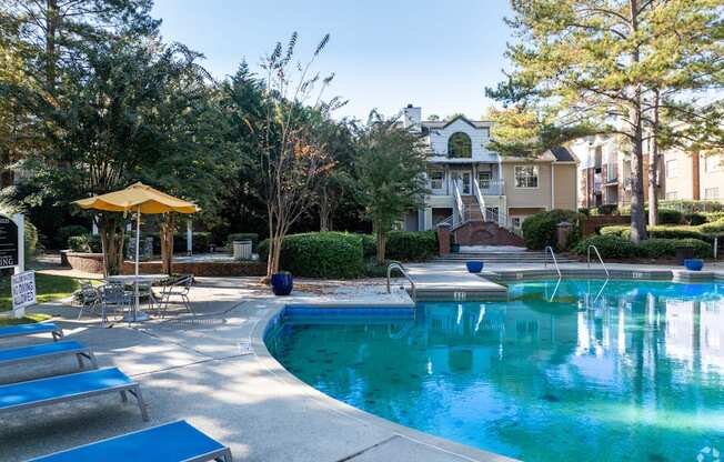 A pool with a yellow umbrella and blue loungers.