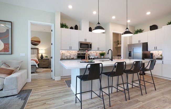 A kitchen with a white island and black barstools.