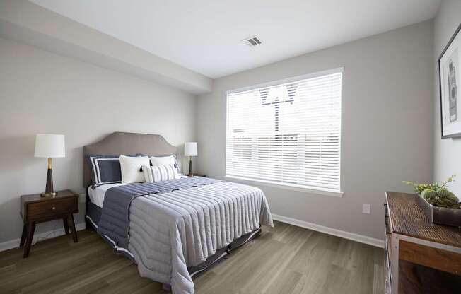 A bedroom with a bed, nightstand, and window at Harbor Pointe Apartments, New Jersey, 07002