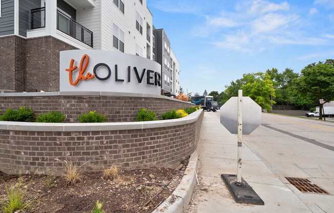 The Oliver apartment complex is located on a quiet street with a sidewalk and landscaping.