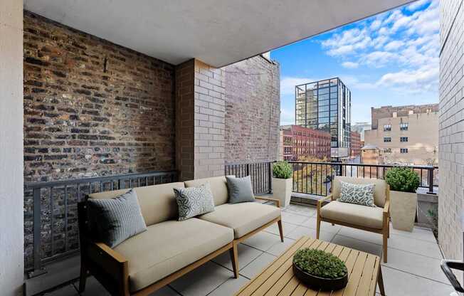 A balcony with a couch, chairs, and a table with a plant on it.