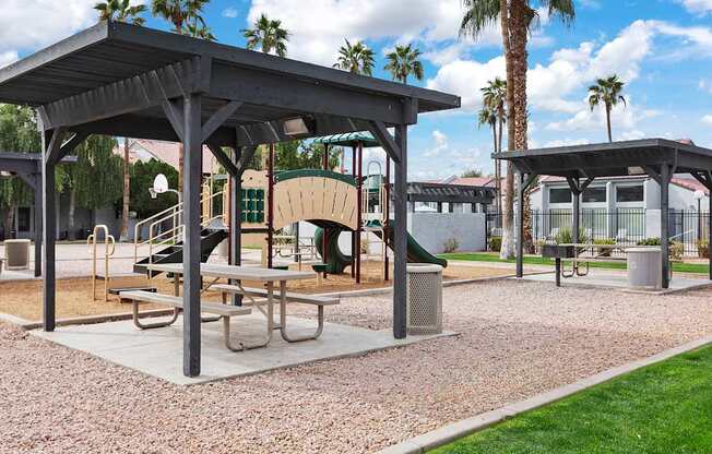 A park with a pavilion, picnic table, and palm trees.
