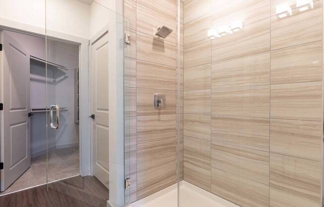 A bathroom with a walk-in shower and a glass door.