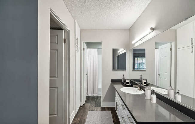 Model Bathroom with White Cabinets and Wood-Style Flooring at Madison Park Apartments located in Anaheim, CA.