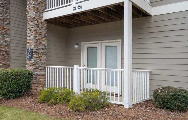 A balcony with a white railing and a glass door is on the second floor of a house.