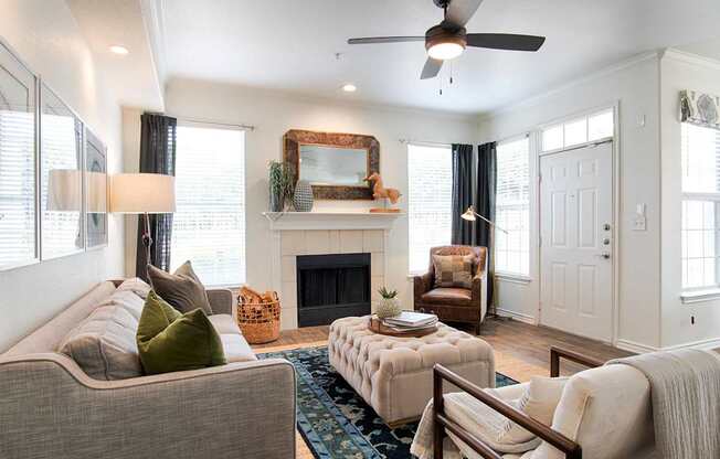 A living room with a grey couch, a fireplace, and a mirror on the wall.