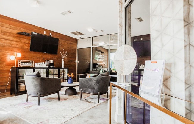 a living room with chairs and a table and a tv on the wall