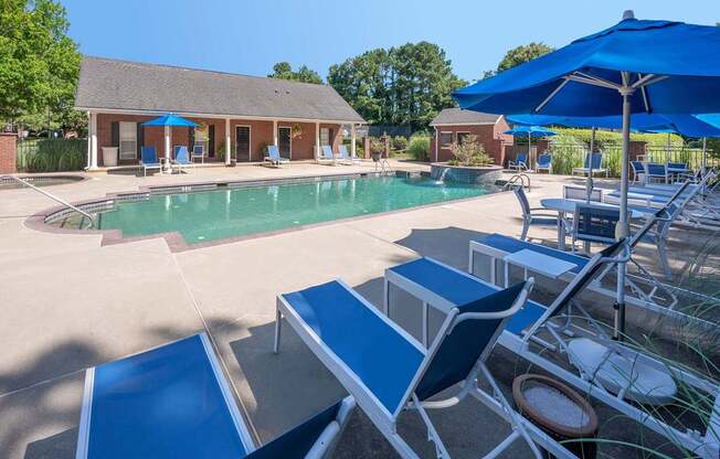 A pool area with sun loungers and a building in the background.