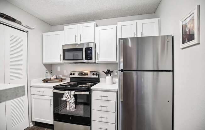 A kitchen with white cabinets and a stainless steel refrigerator.
