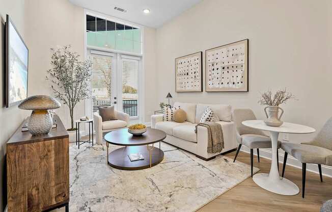A living room with a white couch, a coffee table, and a TV on the wall.