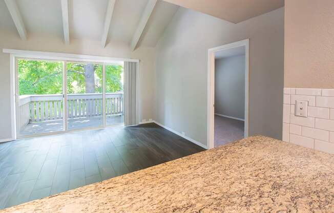 A room with a large bed and a balcony with a view of trees.