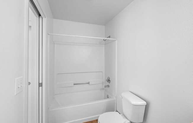 a white bathroom with a toilet and a shower