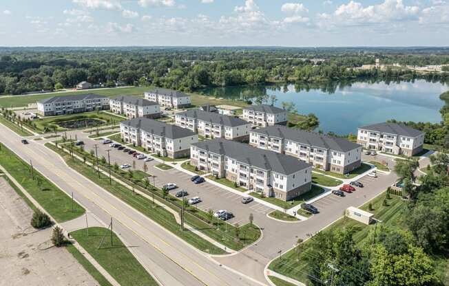 Sky view of the community with large pond behind community. Green grass and paved roads throughout.