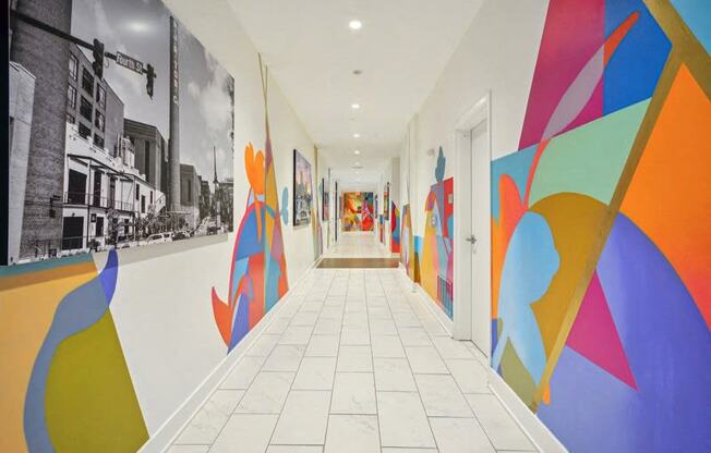 a hallway with colorful paintings on the walls and a white tile floor at Link Apartments® 4th Street, North Carolina, 27101