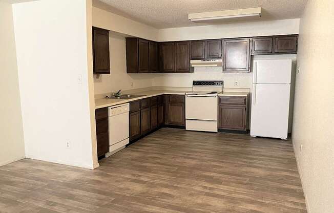 A kitchen with white appliances and brown cabinets.