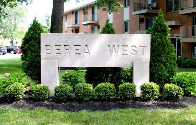 A sign that says "Berea West" is surrounded by bushes and trees.
