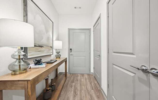 a hallway with a desk with a lamp and a white door