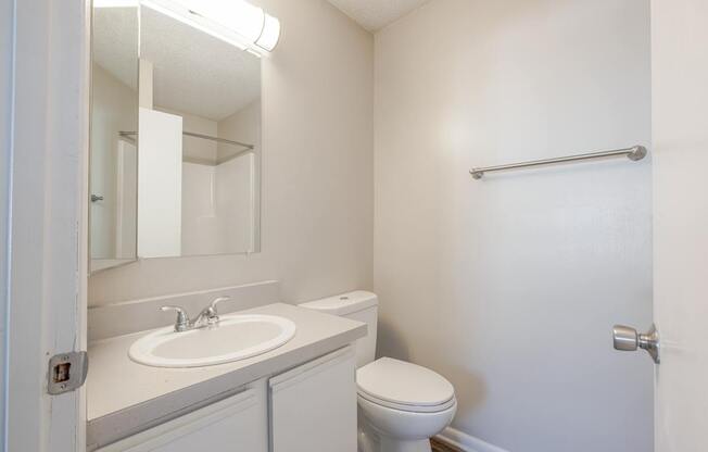 A white bathroom with a toilet, sink, and mirror.