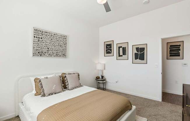 A bedroom with a bed, nightstand, and pictures on the wall.