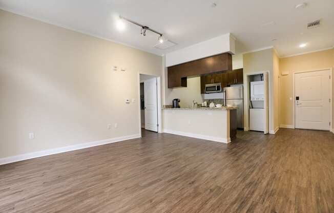 the living room and kitchen of an apartment with a hard wood floor