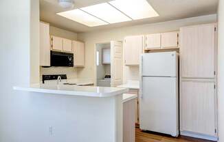 A kitchen with a white refrigerator and cabinets.