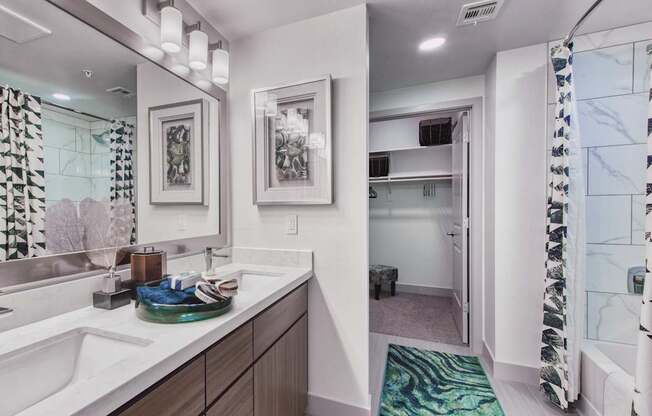 A bathroom with a sink, mirror, and shower.
