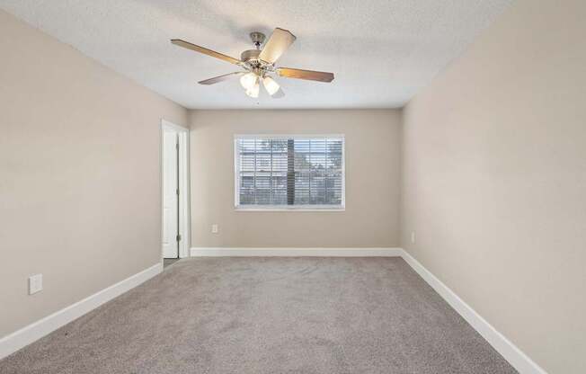 A room with a ceiling fan and a window with blinds.