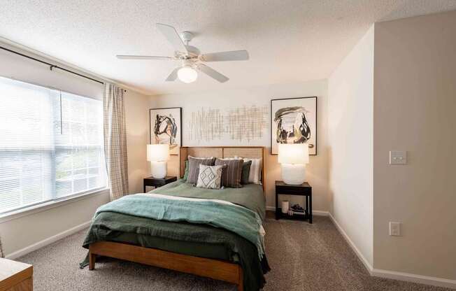 A bedroom with a bed, two lamps, and a ceiling fan.