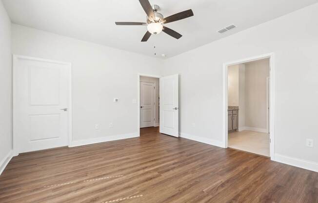 A room with a ceiling fan and wooden flooring.