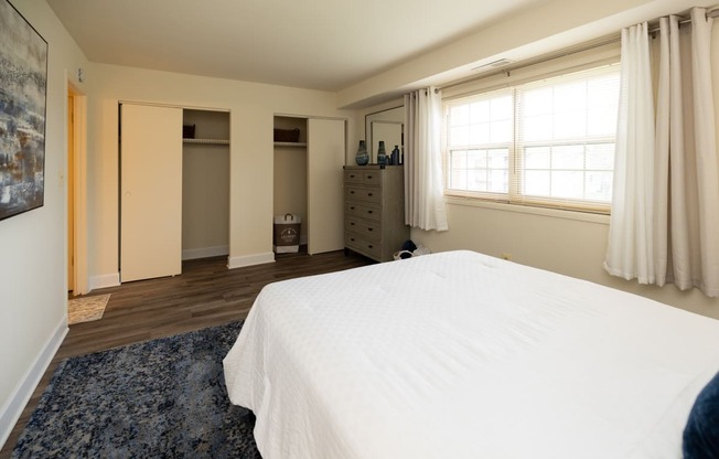 Bedroom with a white bed and a blue rug at Rockdale Gardens Apartments*, Baltimore, MD