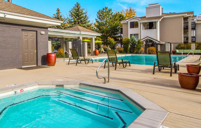 a swimming pool with patio furniture and a spa in front of a house