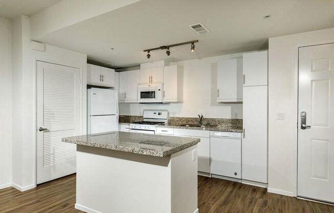 Spacious kitchen with an island and three lights on top of the ceilling