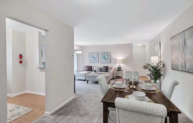 a dining room with a wooden table and chairs and a living room in the background